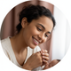 A happy young mother gently touches her baby's hand, looking content and relieved.